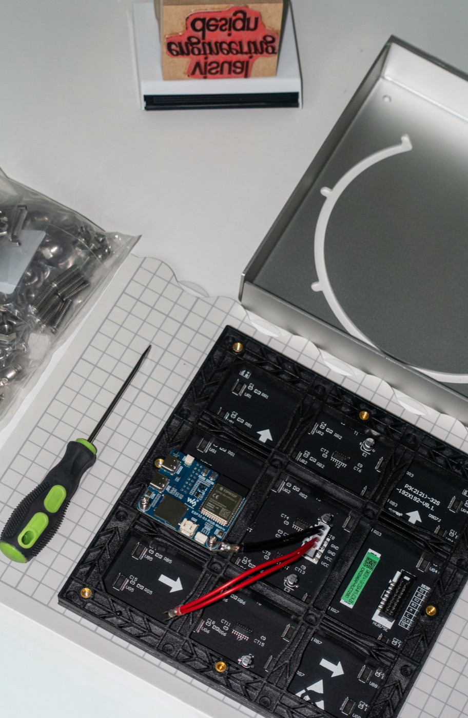 Parts laid out: the panel back with the ESP32 board mounted, the bent backplate, screws and a driver